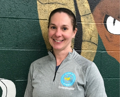 Middle-aged female running coach standing against a painted brick wall