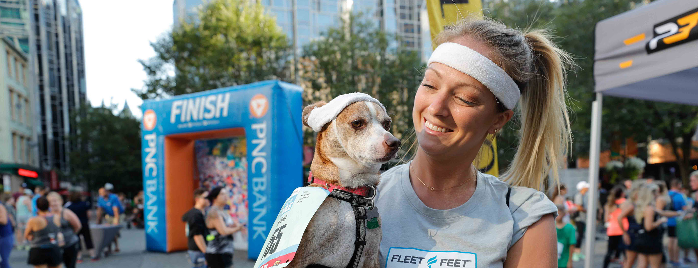 Woman holding her dog near the finish line of the Fleet Feet Liberty Mile race