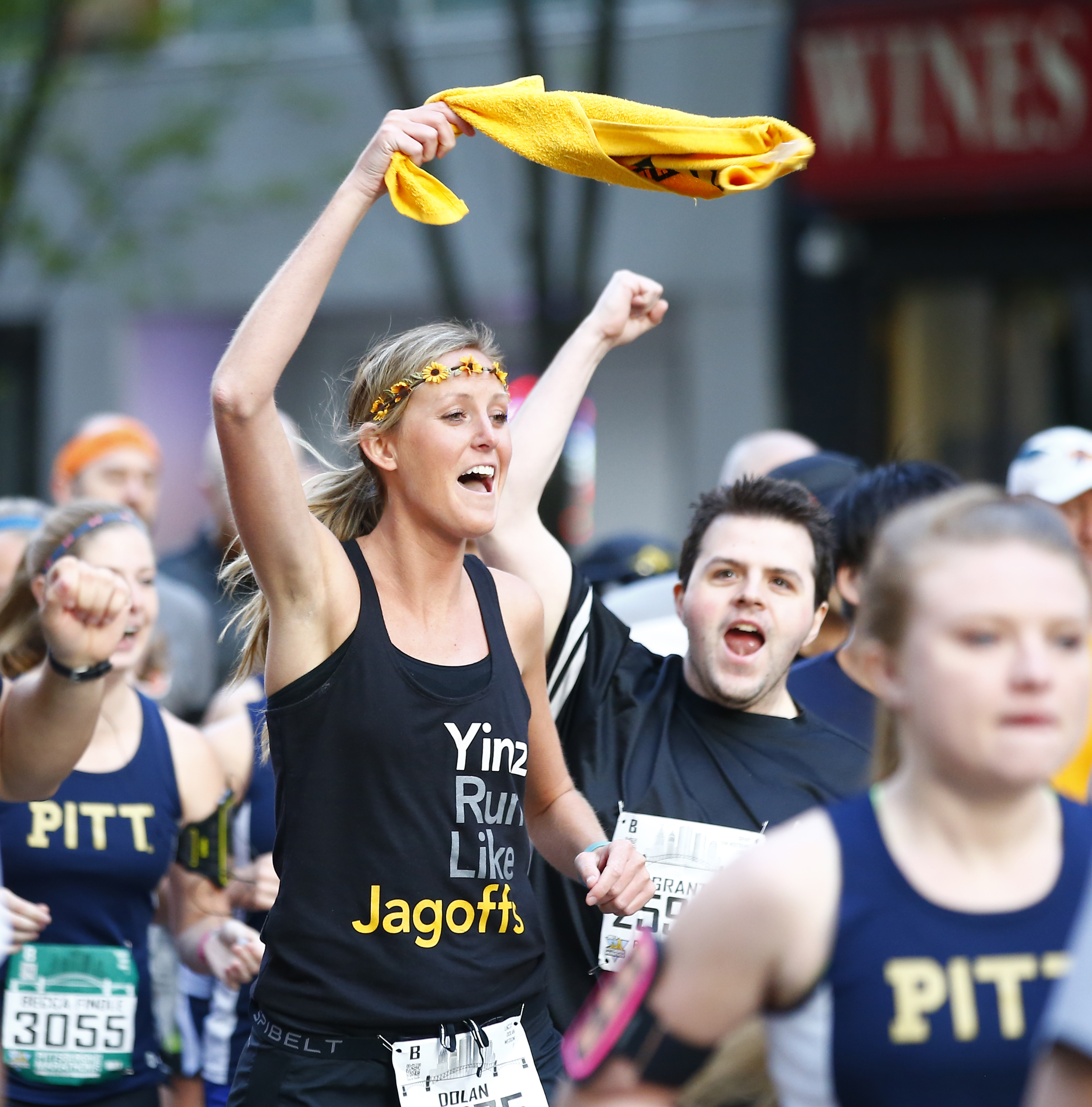 Young woman is waving a Steelers Terrible Towel in a crowd of runners.