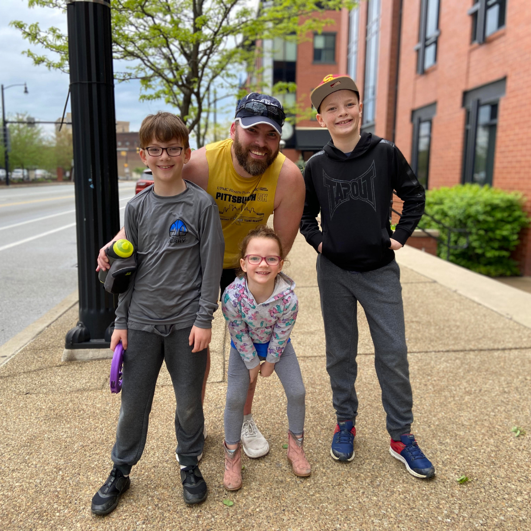 P3Runner Derek Long and three of his four children on a sidewalk in Pittsburgh.