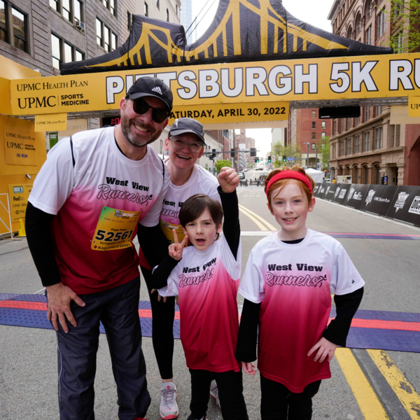 Young girl running in the UPMC Health Plan/UPMC Sports Medicine Pittsburgh 5K gives high-five to young woman