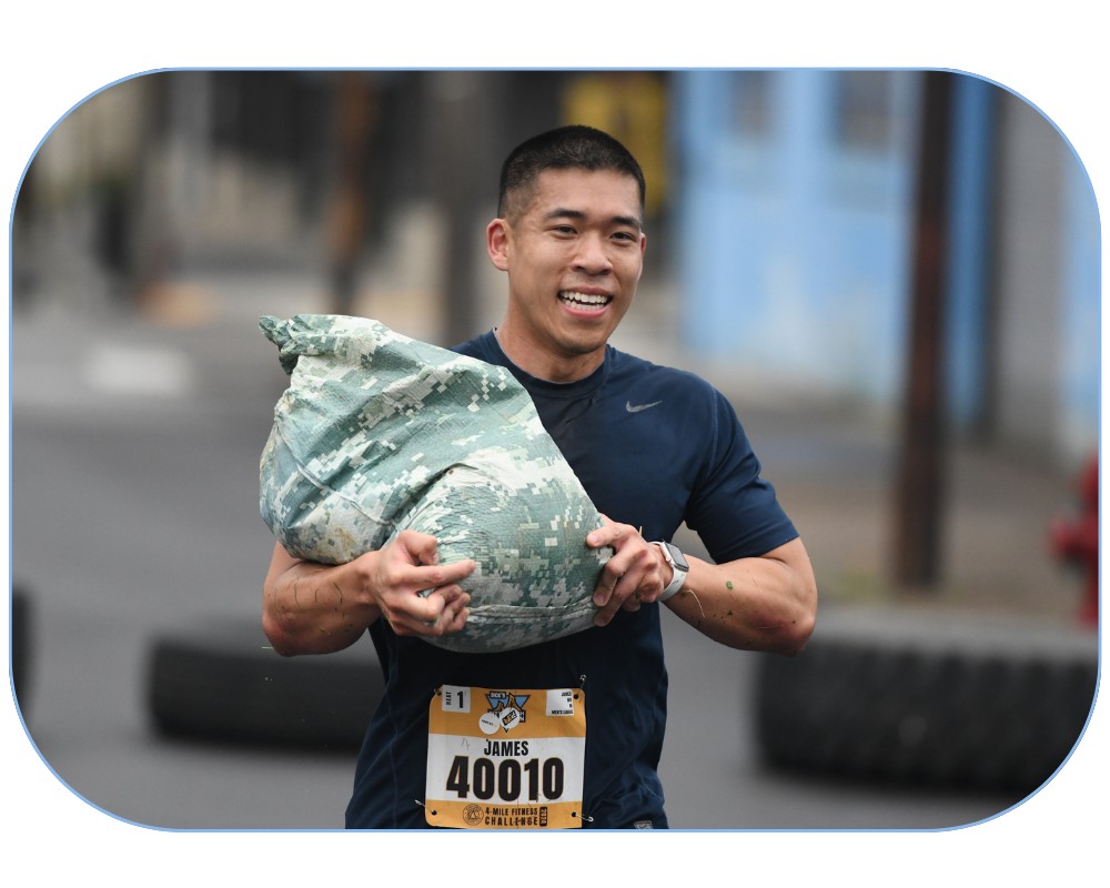 Adult male participant carrying a camo-printed sandbag during the 4-Mile Fitness Challenge