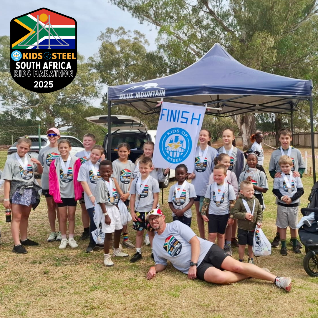 A group of children smile around a Kids of Steel banner